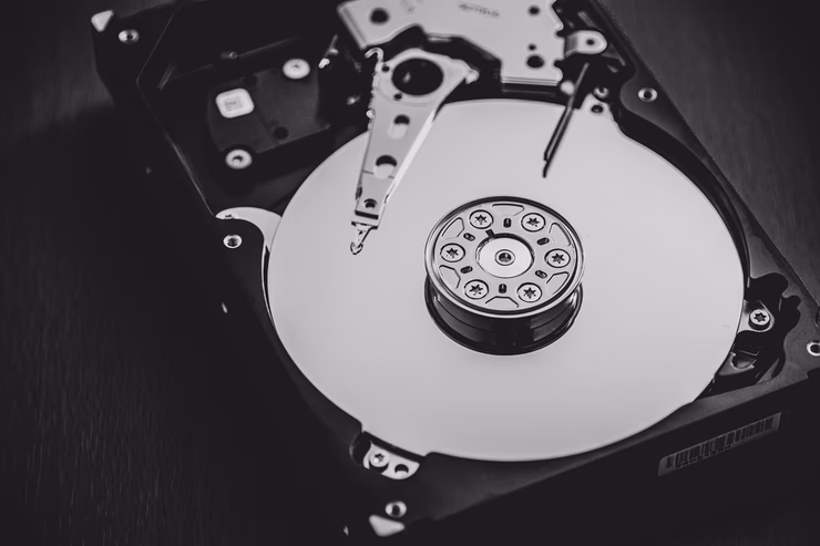 HDDの内部構造のモノクロ写真。高速回転するプラッタと読み書きヘッドが見える